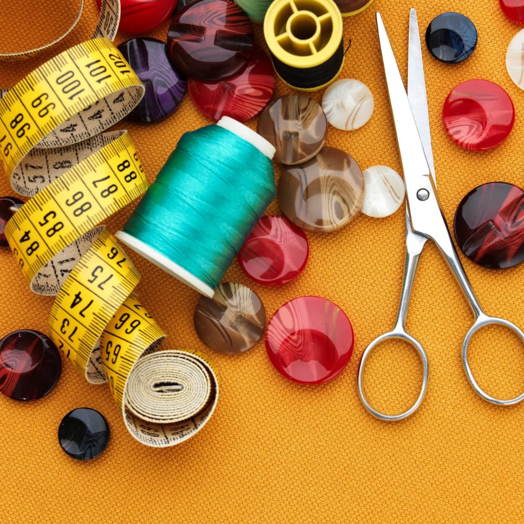 Fita métrica, tesoura, botões e carretéis de linha em flat lay de aviamentos de costura